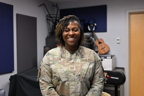 Woman in military uniform smiling in a music room.