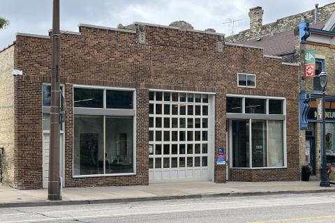 Brick storefront with large glass windows and garage door.