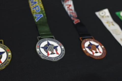Three National Veterans Golden Age Games rest on a table with two additional award ribbons.