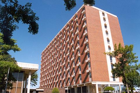 Tall brick building with many windows and trees.