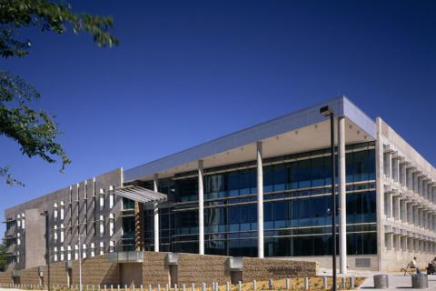 Modern building with glass windows and brick facade under clear blue sky.
