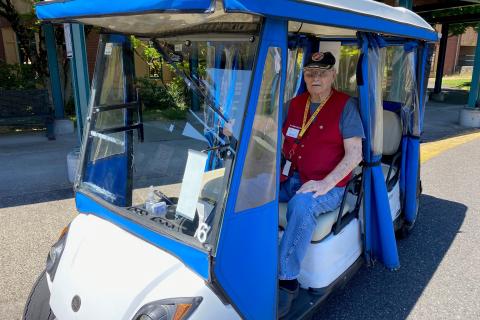 Veteran in a blue and white golf cart on a road.