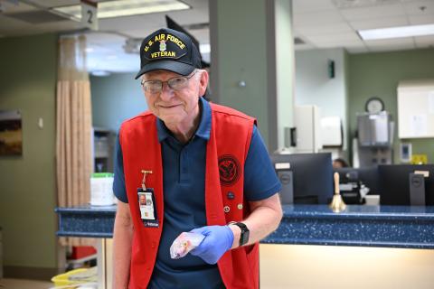 Veteran with red vest and blue gloves at a hospital counter.