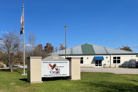 Building with green roof, flag, and sign on lawn.