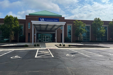 Empty parking lot in front of a large brown building with a blue canopy.