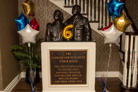 Statue of two people, a large number 6, and colorful balloons.