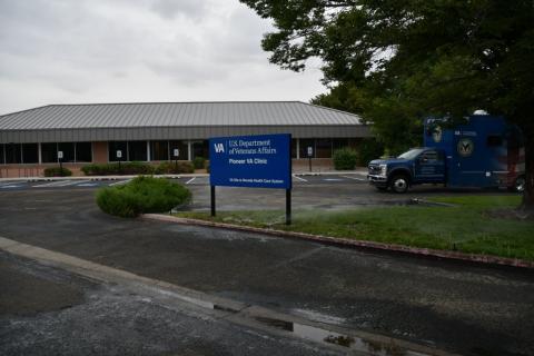 Blue sign and parked vehicle in front of a building.