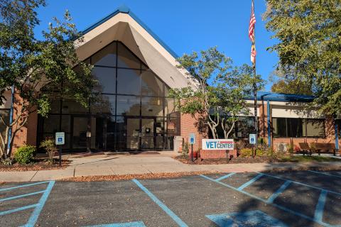 Modern building with glass facade, flag, and blue parking spots.