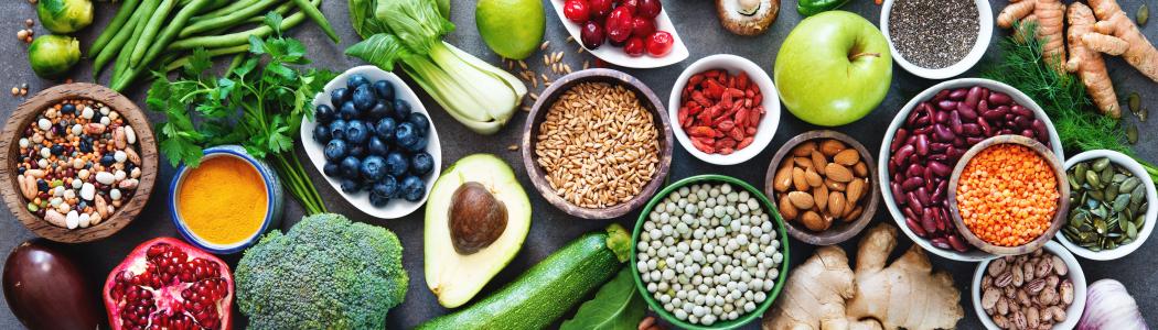 Stock image of a variety of healthy foods including pomegranates, avocados, cucumbers, broccoli, and more.