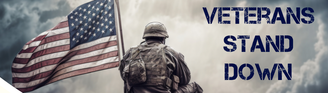 A soldier kneels down near a United States flag. Overlaying the cloudy sky, text in military-style stencil say Veterans Stand Down.