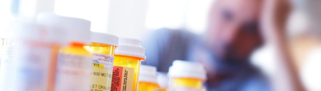Veteran looking at medication bottles on a countertop.