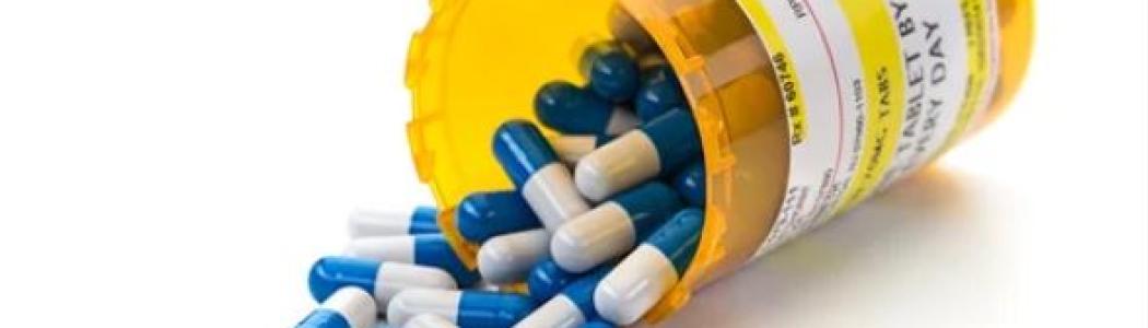 Open medication bottle spilling prescription gel capsules