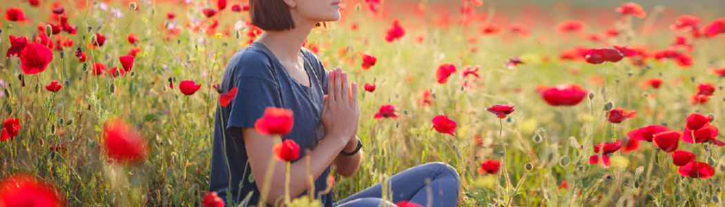 Woman meditating in field of poppies