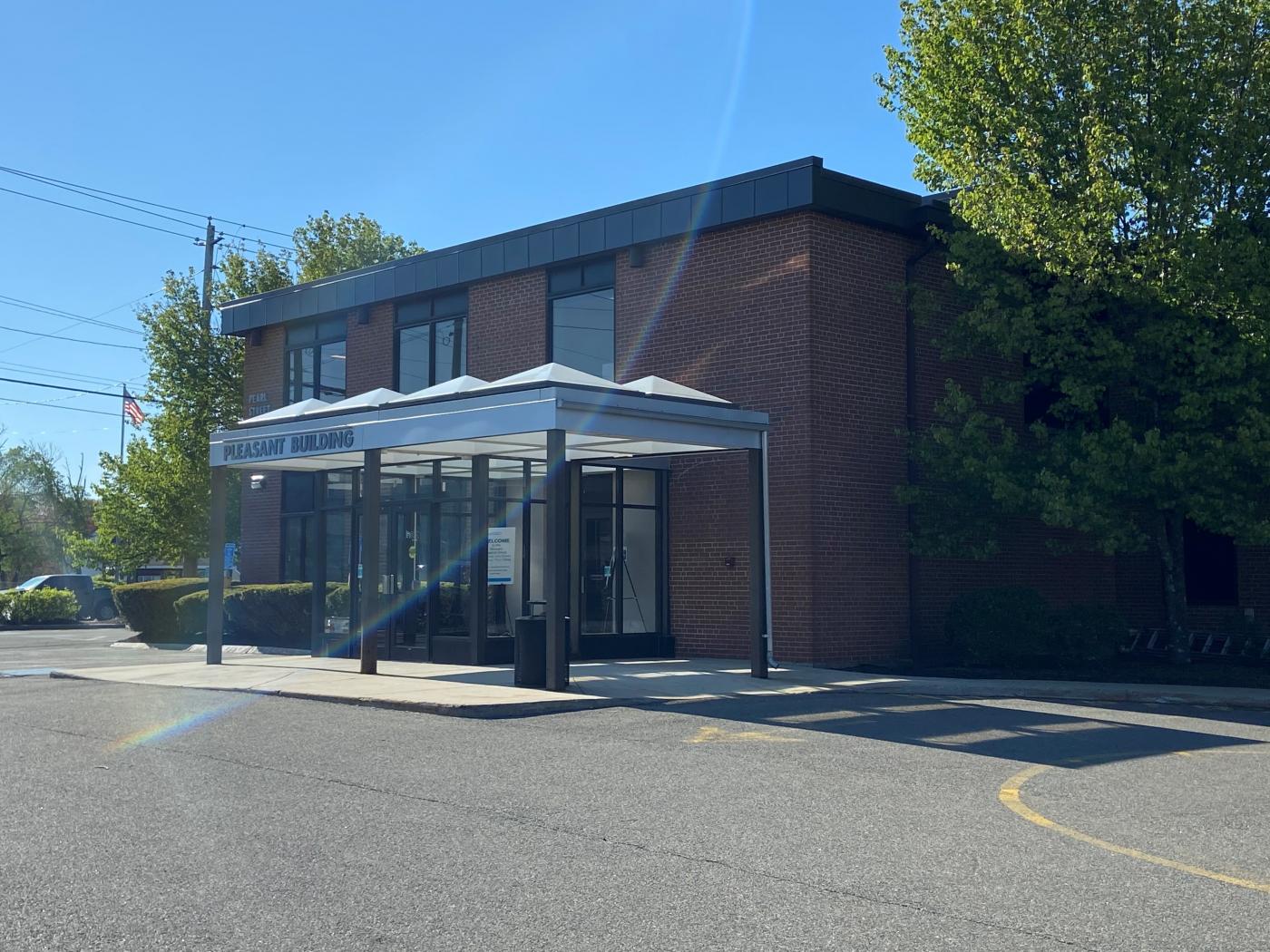 Front entrance of the Pleasant Building that faces the intersection of Pearl Street and Pleasants Street. Picture is taken from the Veteran reserved parking spots