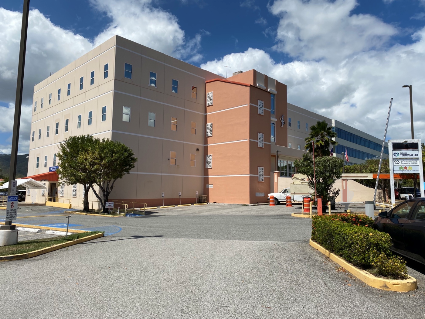 Four story beige and peach colored building with parking lot to left side of building