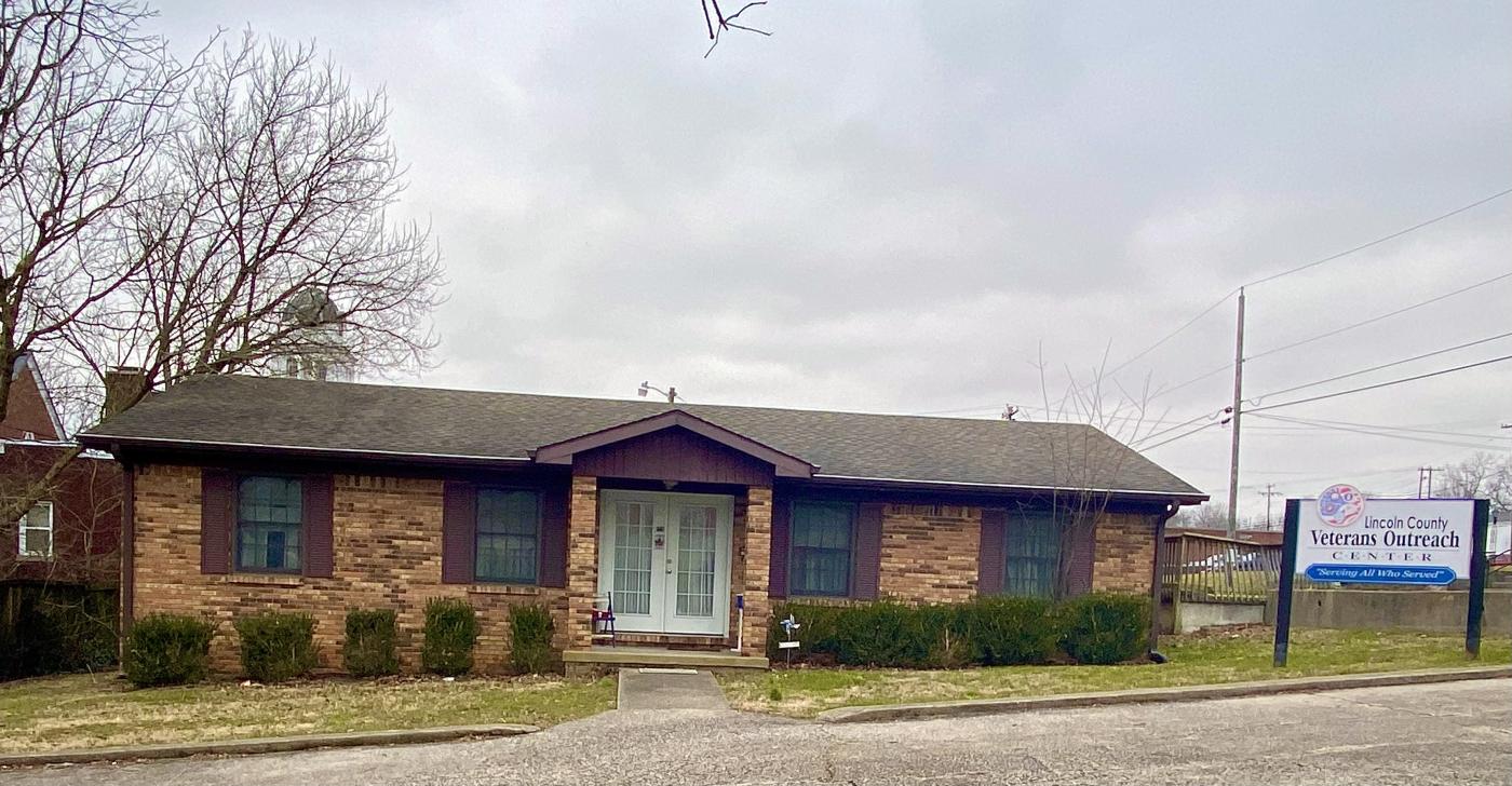 Photo of brick building with front porch and white double doors.