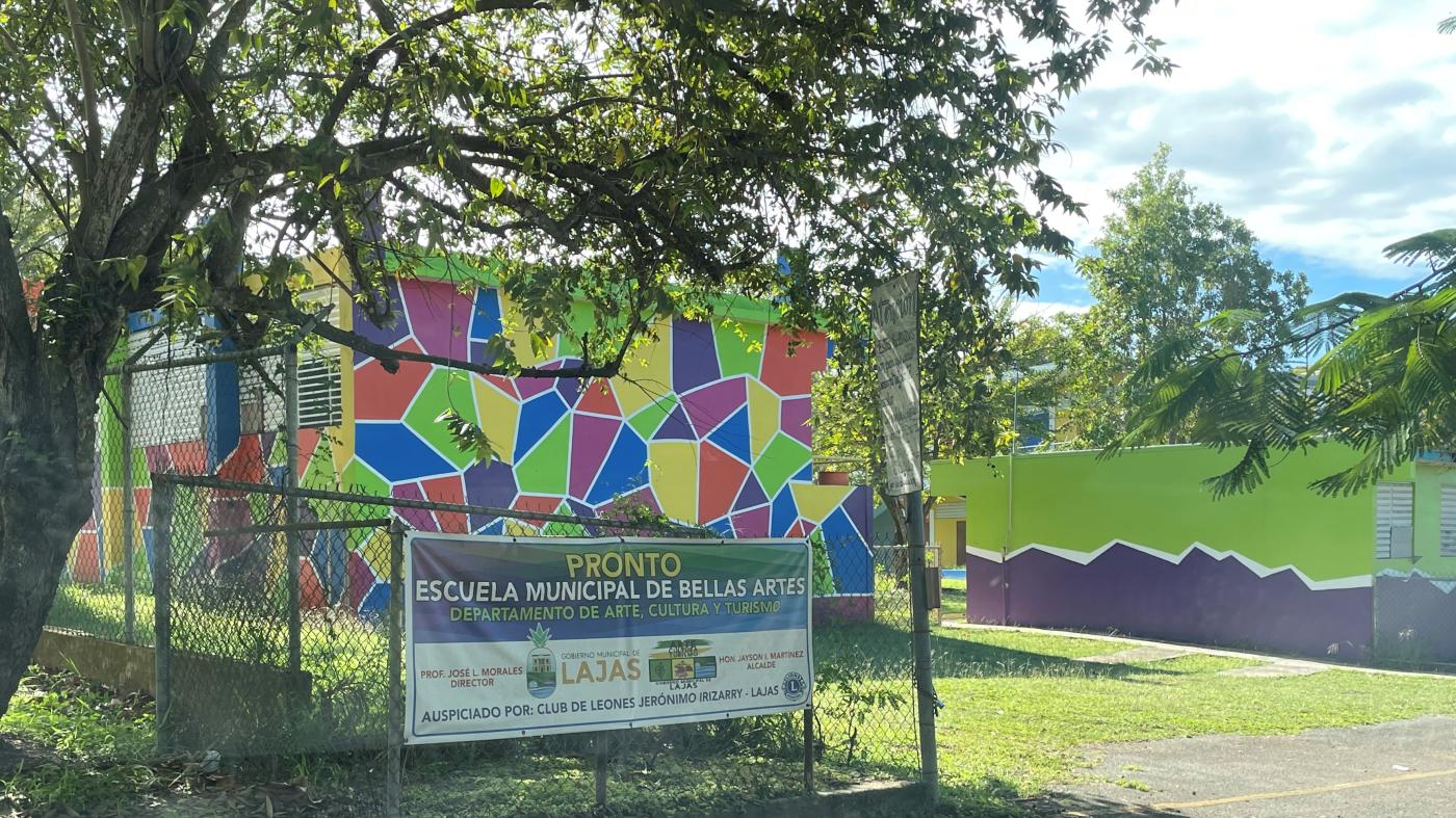 Multi-colored building across from green and purple building located behind a fenced area