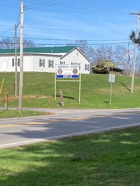 White building with green roof on hill with flag and tank.