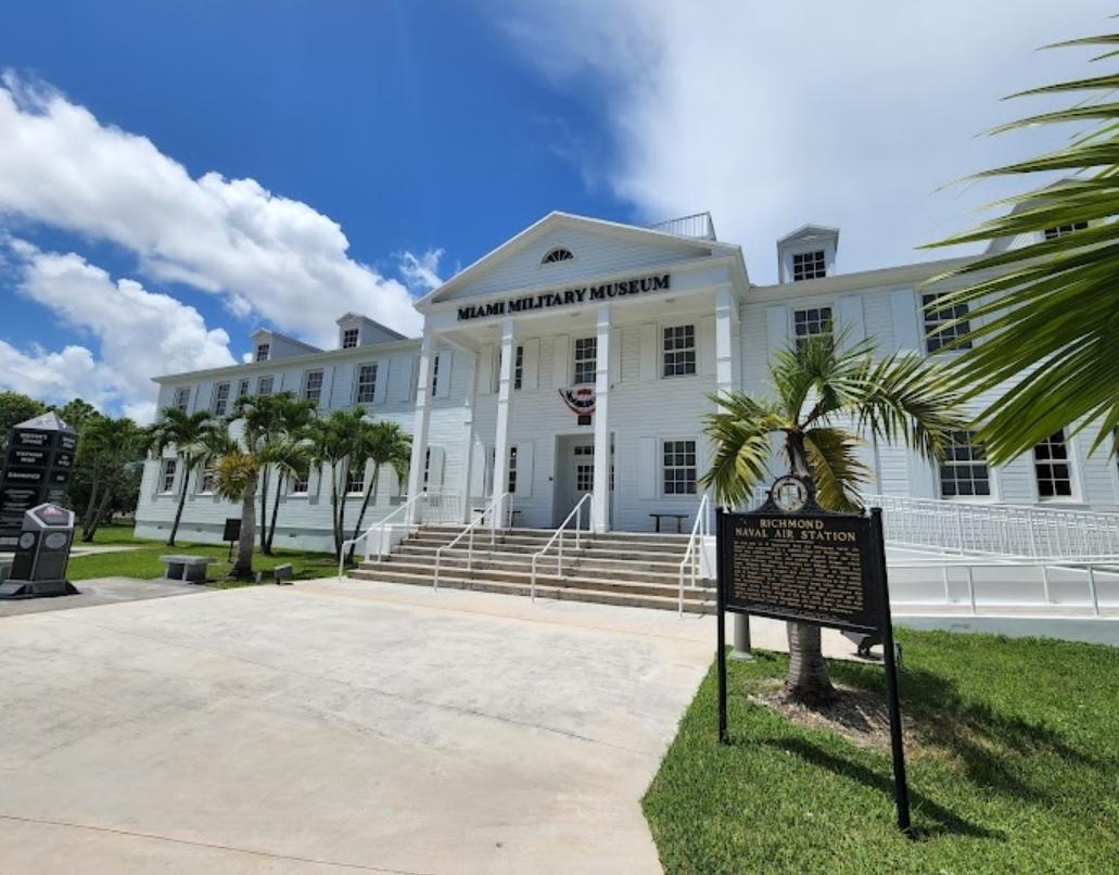 Image of the front facing white building which is the Miami Military Museum and Memorial. Above the face of the building reads 'Miami Military Museum and Memorial' in black.