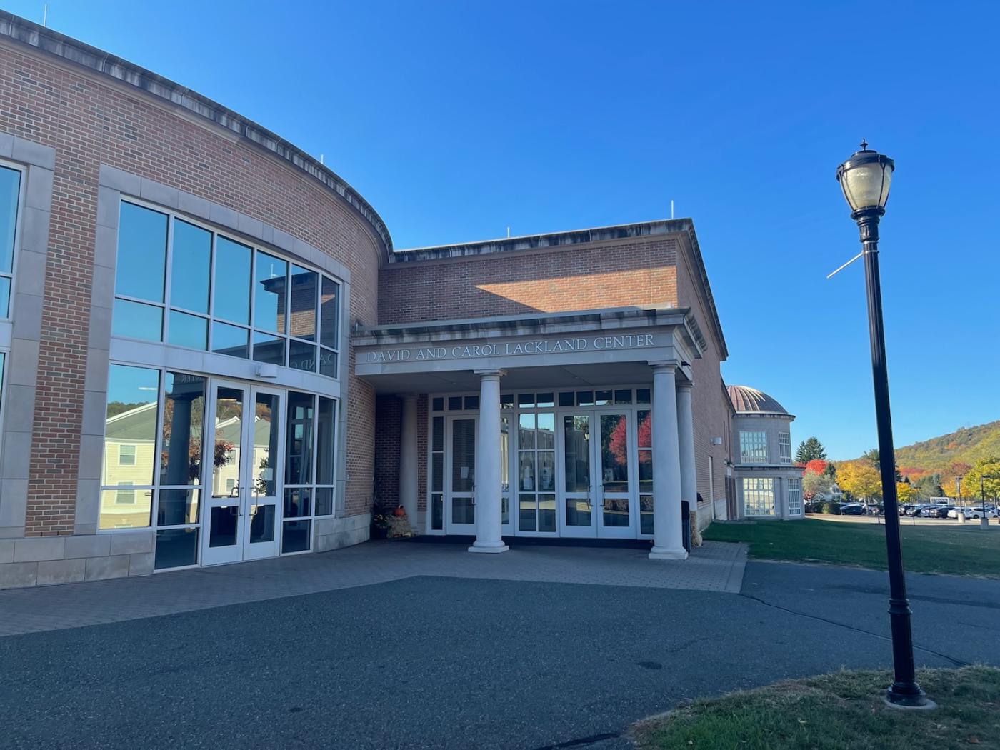 The building has large glass windows and doors and two large white pillars at the entrance. These pillars stand out against the red brick building.
