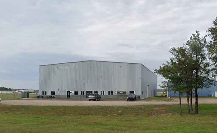 A large grey building in a rural area