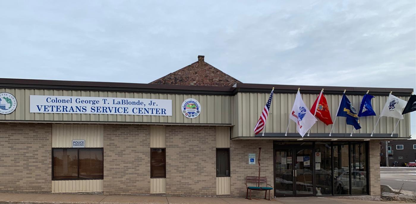 A brown building with military branch flags at the entrance