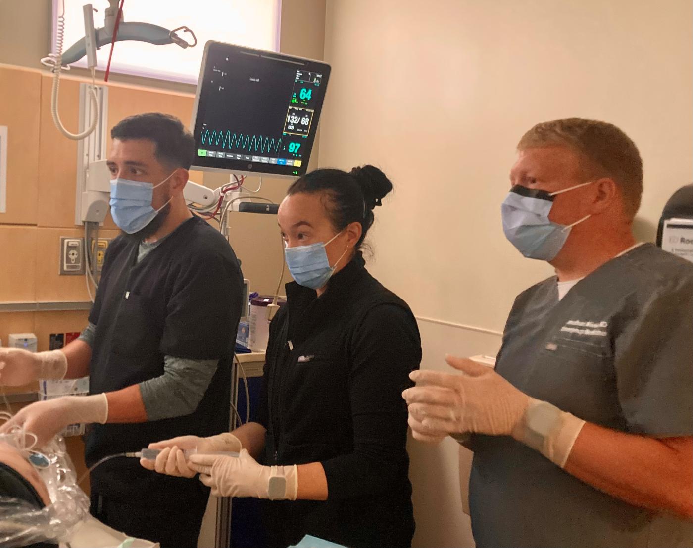 Residents, doctor working in an emergency room training scenario.