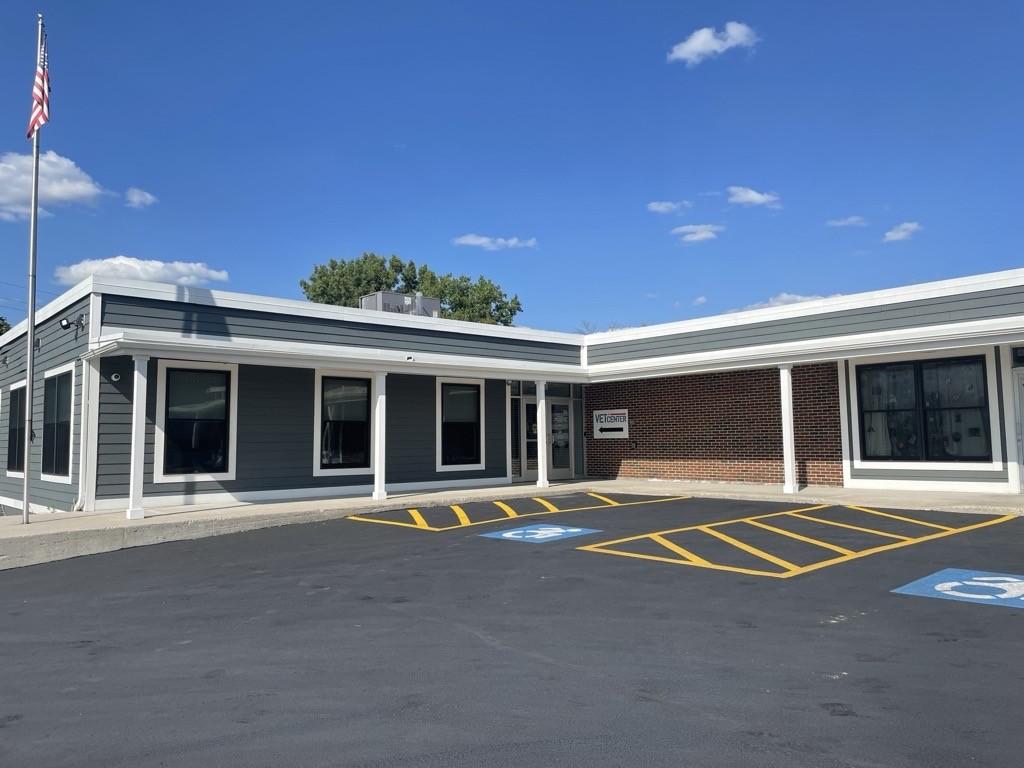 "L" shaped building with brick and lap siding. Entrance at inside corner.