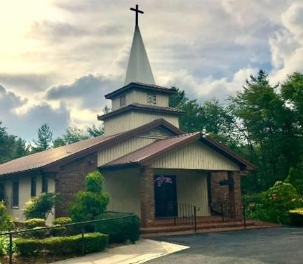 Brick and tan structure with chapel and cross adorning the building