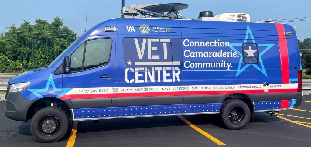 Mercedes Sprinter van. Blue vehicle wrap with red and white stripes. Vet Center logo and slogan.
