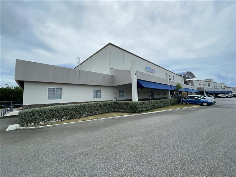 Ponce Vet Center Exterior is a light beige building with grey molding on the roof and blue canvas curtains across the front.