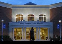 Illuminated Boone County Public Library at night with a statue in front.
