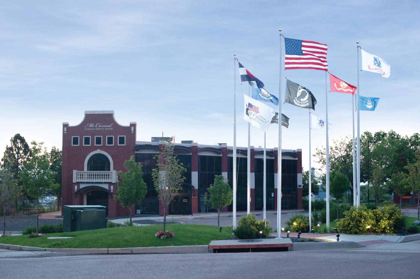 American and state flags in front of a brick building.