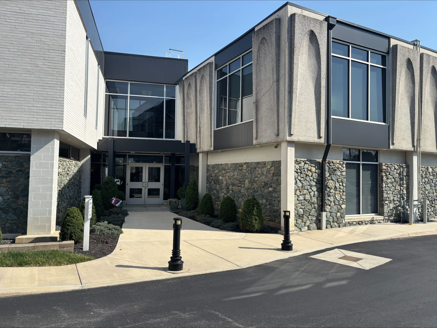 Modern building with glass windows, stone facade, and entrance walkway.