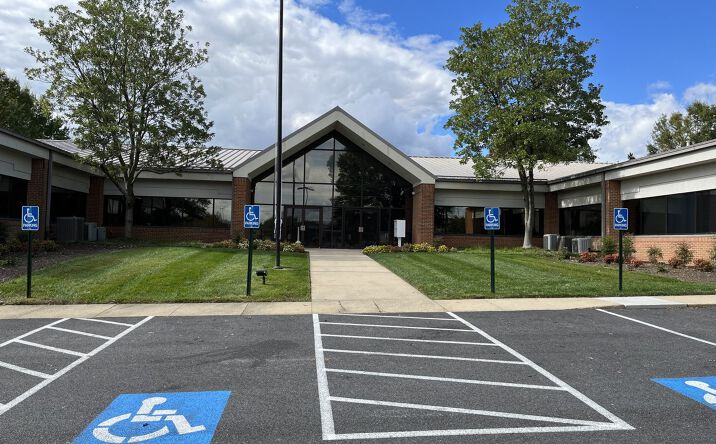 Entrance to a public building with parking spaces and handicap signs.