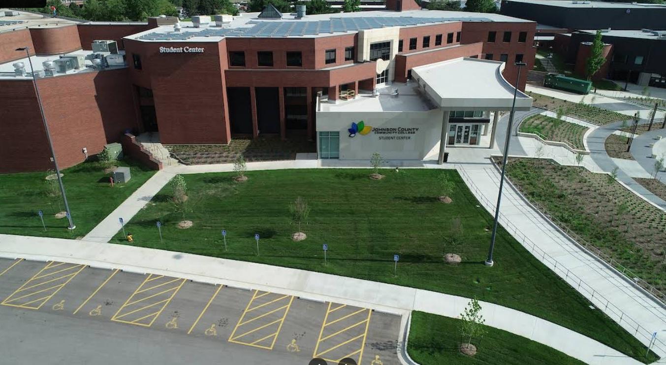 Aerial view of a modern building with green lawns and solar panels on the roof.