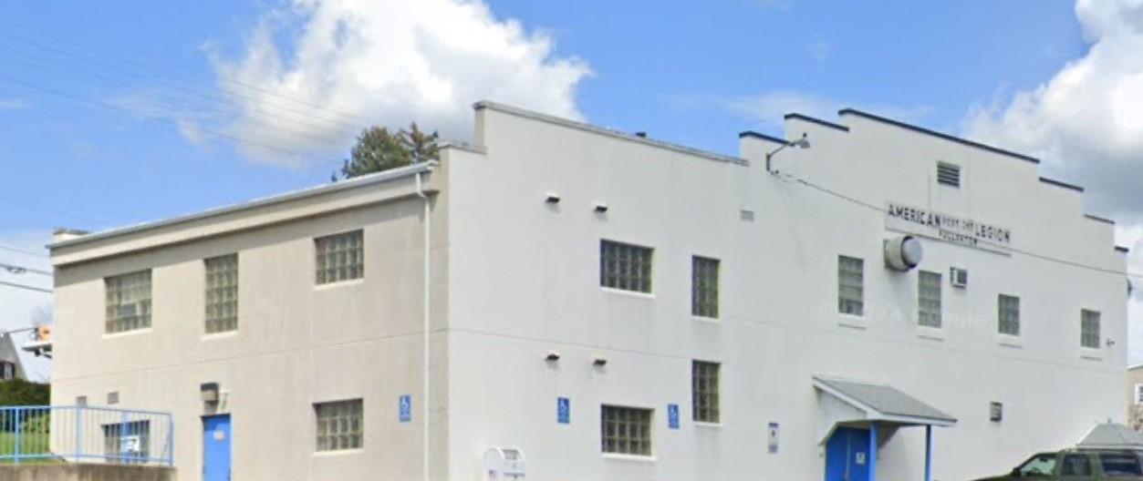 White building with blue doors and windows under blue sky with clouds.