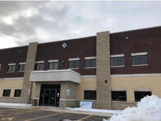 Modern brick office building with snow on ground, cloudy sky.