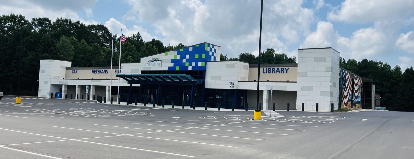 Empty parking lot in front of large white building.