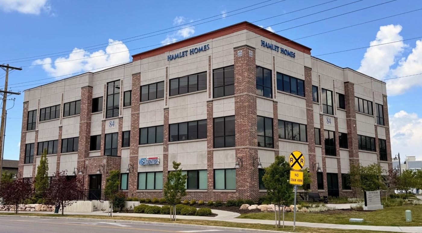 Salt Lake Vet Center located in a modern office building with many windows, greenery, and a yellow yield sign.