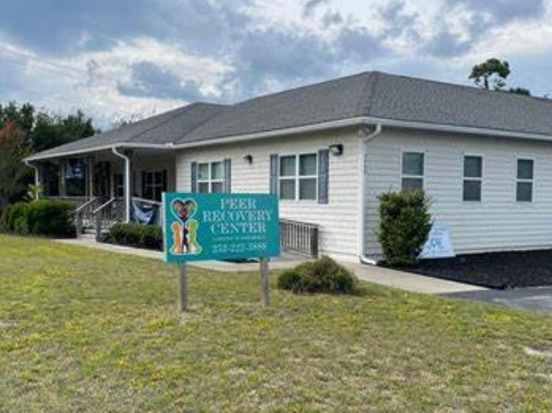 Green sign in front of white building on green grass.