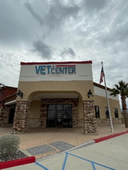 Vet Center building with flag, cloudy sky, and palm trees.