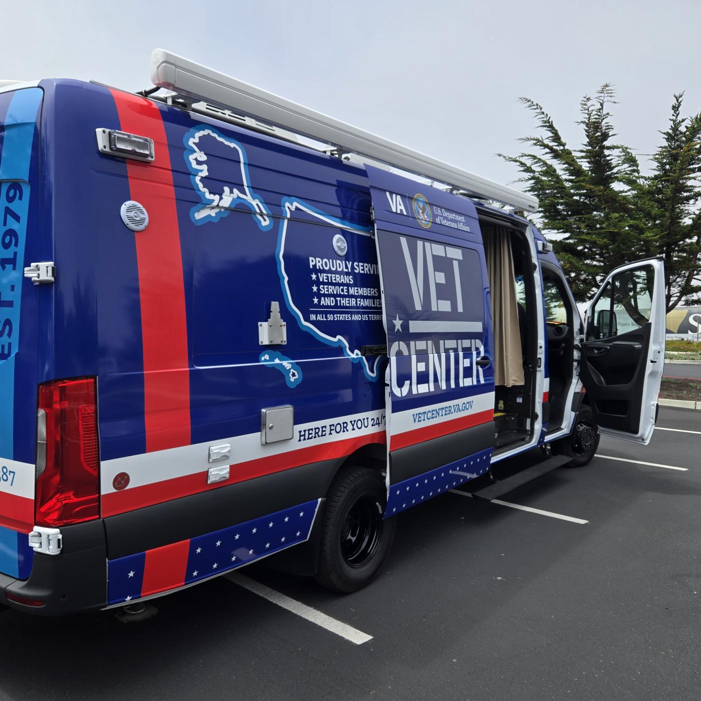 Blue and red van with "Vet Center" text and US map graphic parked in lot.