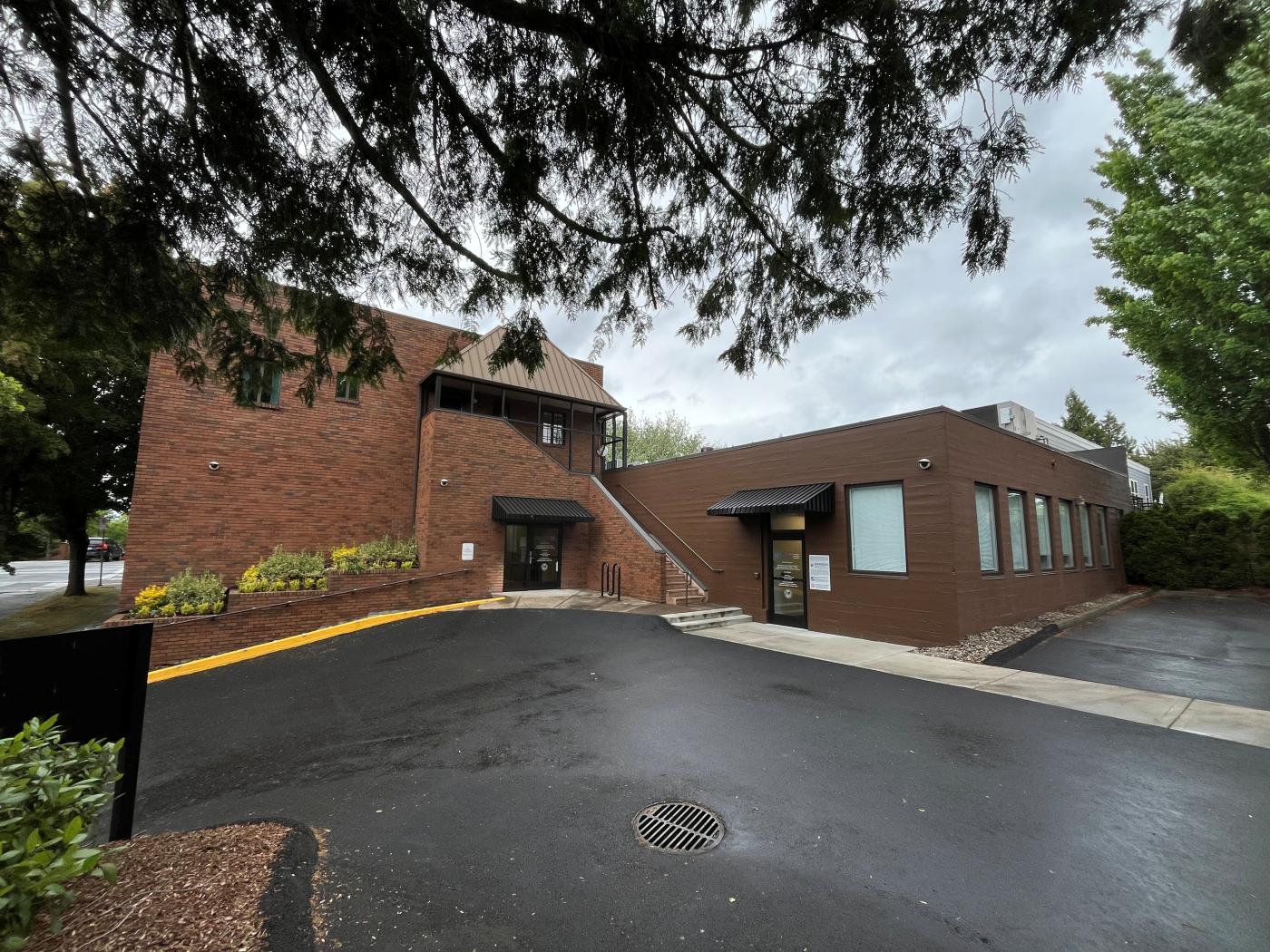 Brown office building with black awnings and empty parking lot.