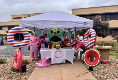 People under a canopy with inflatable toys at a school event.