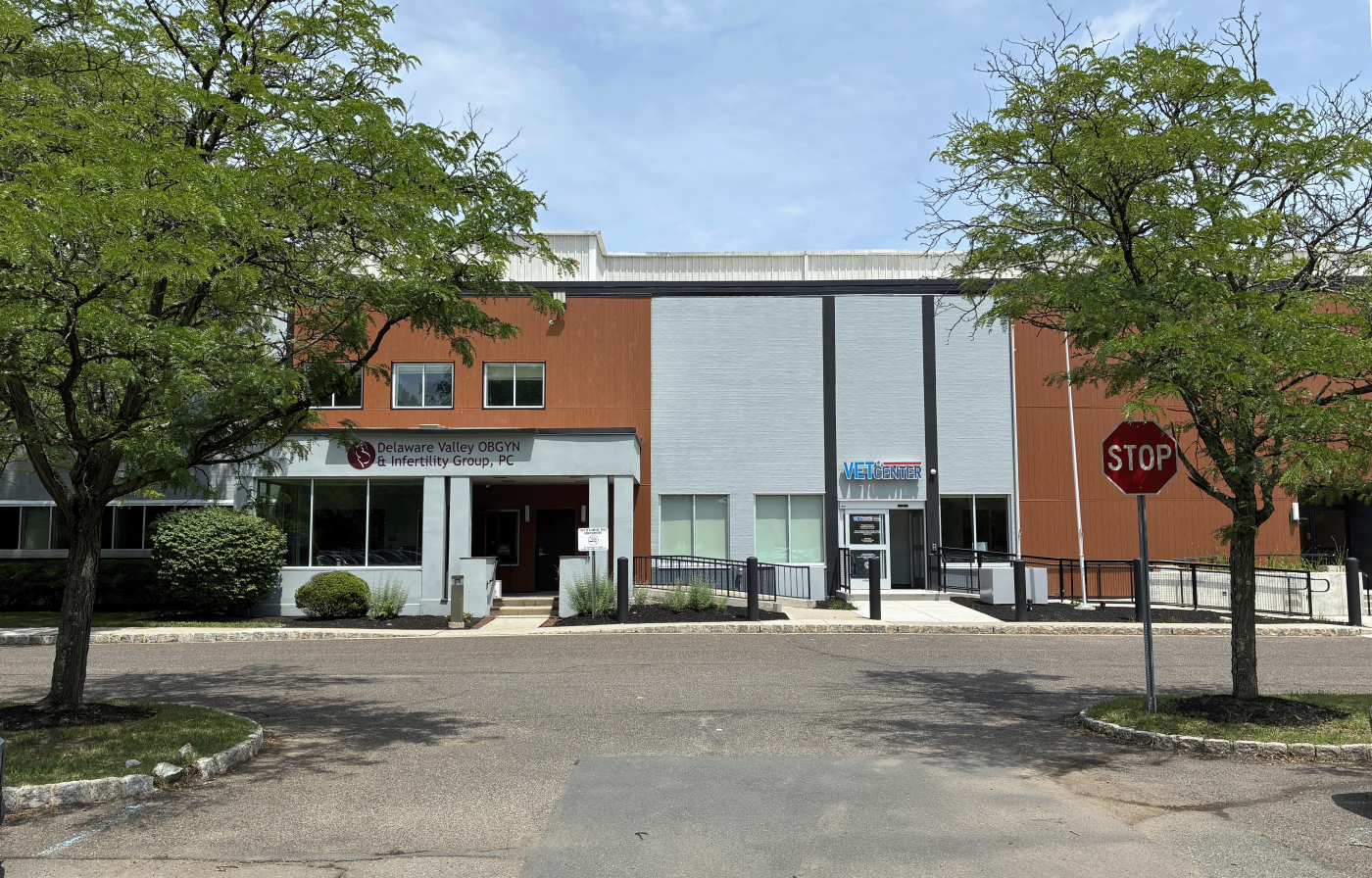 Exterior of building with orange and gray panels, trees, and stop sign.