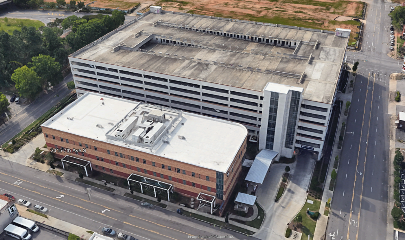 Aerial view of two buildings, a parking garage, and an office building.