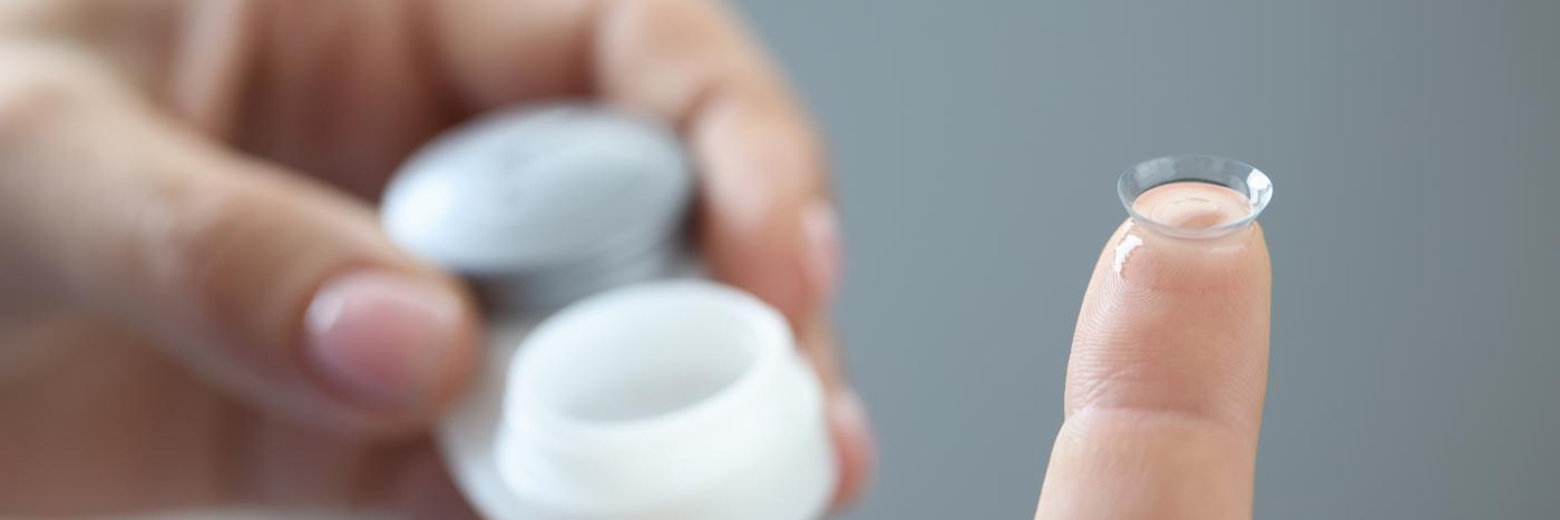 Close-up of hands placing a contact lens on a finger.