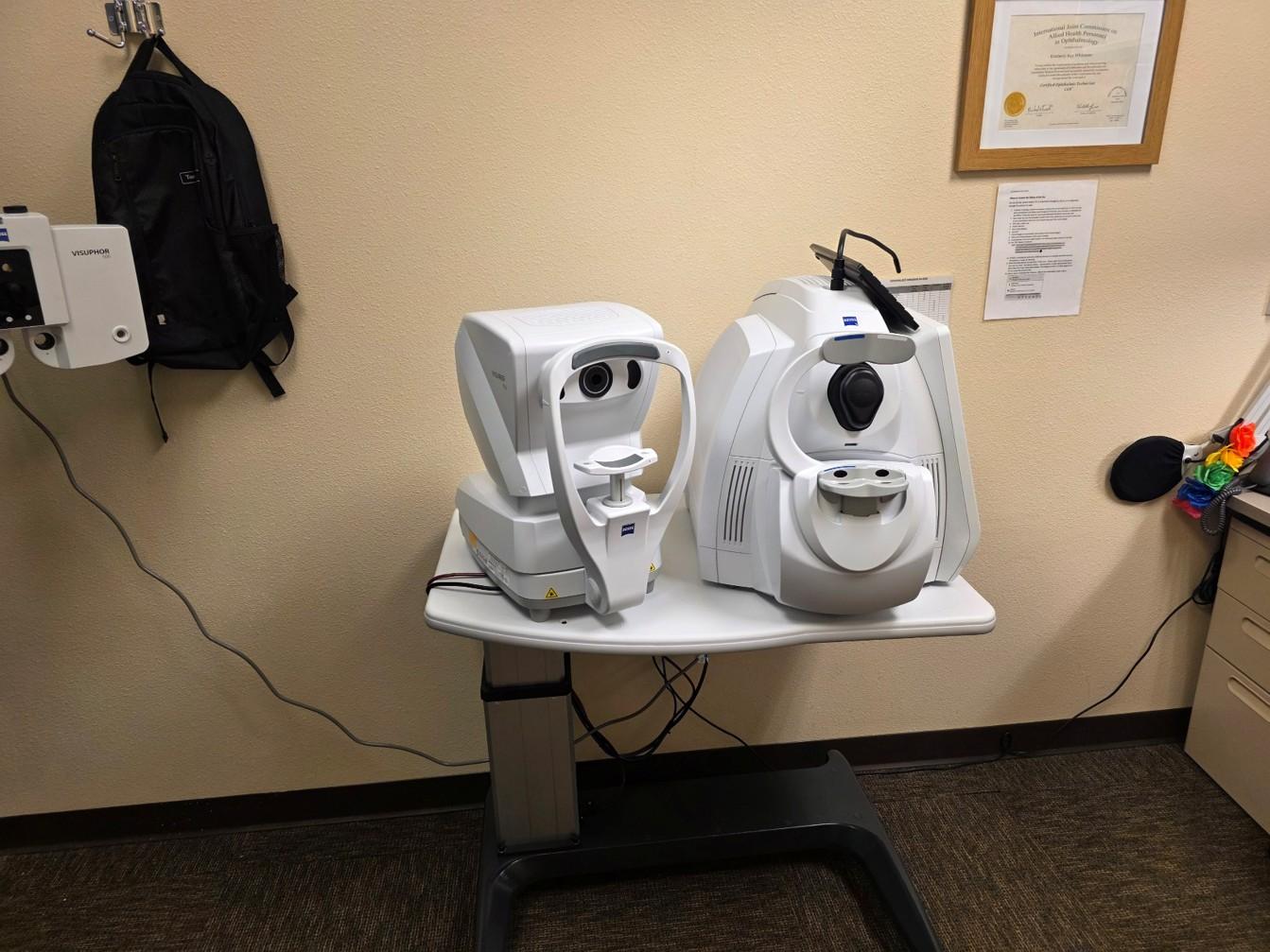 Two eye exam machines on a white table in a room.