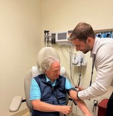 Doctor checking blood pressure of male patient in clinic.